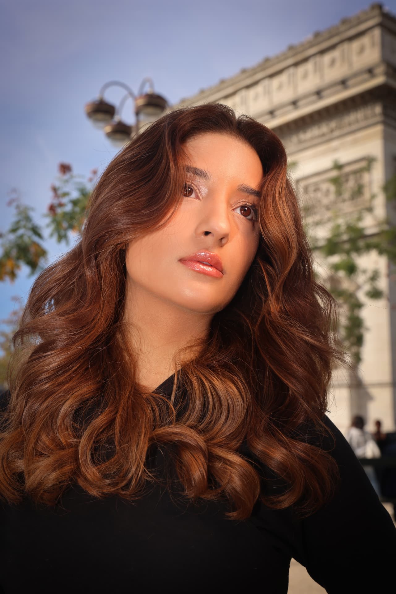 Close de maquilhagem iluminada com lábios glossy e ondas castanhas